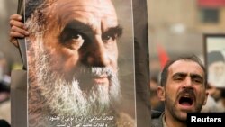 تہران میں 30 دسمبر 2009 کو یوم عاشور کے موقع پر اپوزیشن کے مظاہروں کے خلاف ر حکومت کے حامیوں کے احتجاج کے دوران ایک شخص اسلامی جمہوریہ ایران کے بانی آیت اللہ روح اللہ خمینی کی تصویر اٹھائے ہوئے ہے
