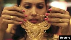 Nhân viên bán hàng cho khách hàng xem một sợi dây chuyền vàng tại một cửa hàng nữ trang ở thành phố phía bắc Ấn Độ Chandigarh.