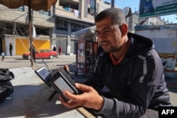 غزہ کے علاقے رفح میں ایک فلسطینی دکاندار اپنی دکان پر یڈیو سن رہے ہیں ، فوٹو اے ایف پی 19 دسمبر 2023