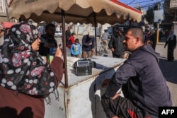 رفح میں ایک پناہ گزین کیمپ میں ایک فلسطینی دکاندار ریڈیو سن رہا ہے، فوٹو اے ایف پی 19 دسمبر 2023